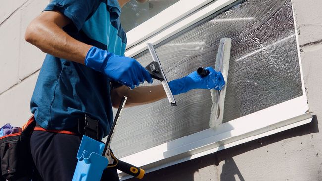 Mann putzt Fenster